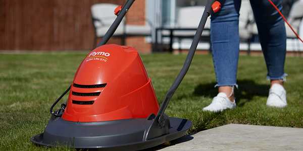 A woman mowing a lawn using a Flymo® Turbo Lite hover lawnmower.